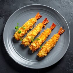 Camarões em tempura crocante servidos em prato de cerâmica