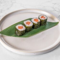 Hosomaki de salmão servido sobre folha verde em prato de cerâmica
